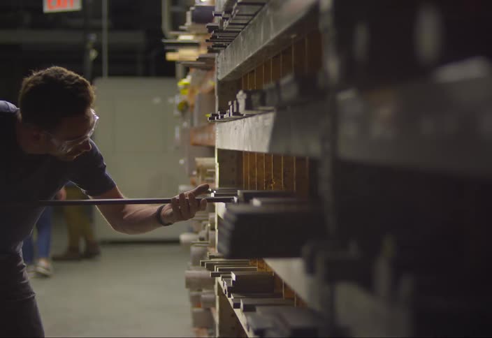 A man retrieves a piece of wood from a shelf and walks away
