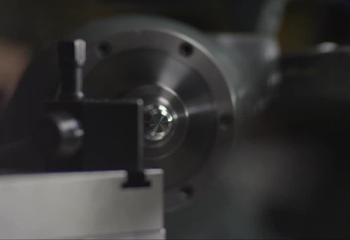 Closeup of a lathe and a hand operating it