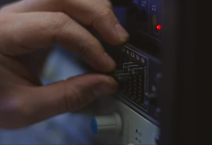 A white hand adjusts switches on a machine