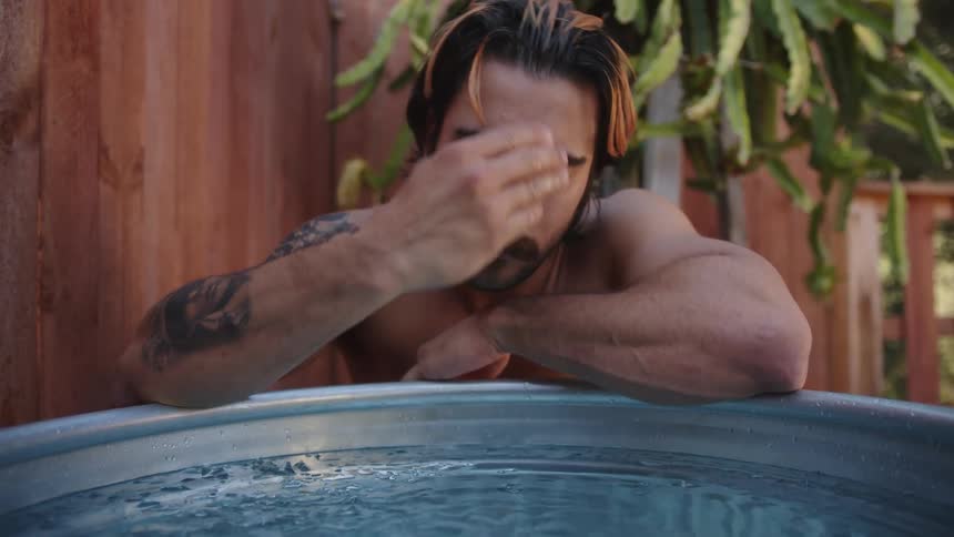 A man puts his hand in some water then slicks his hair back