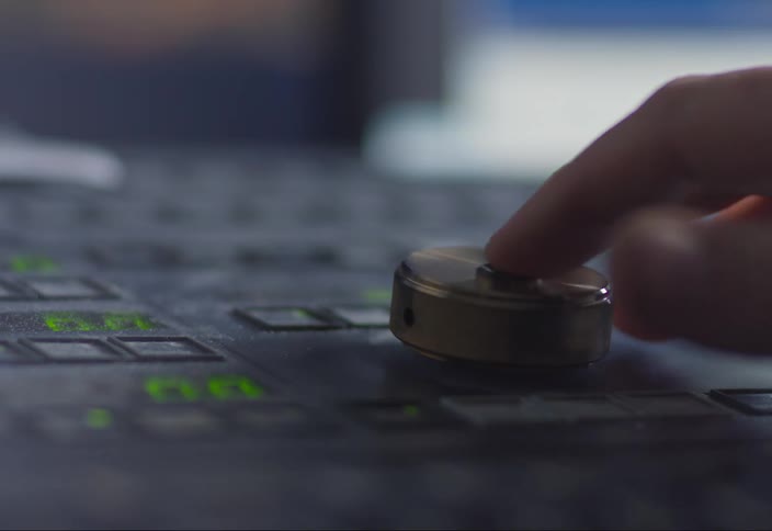 A human hand using its finger to turn a round button that is on an electronic table