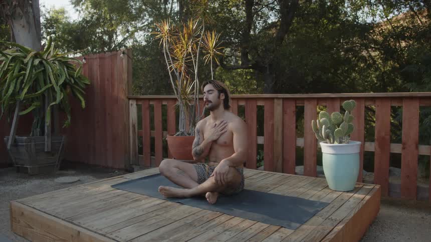 Shirtless man sitting meditating