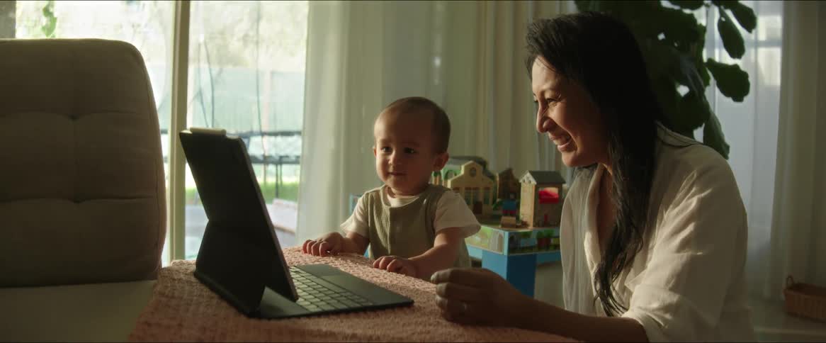 A mother interacts with her child while using a tablet computer
