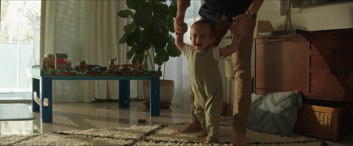 A parent helps their baby walk