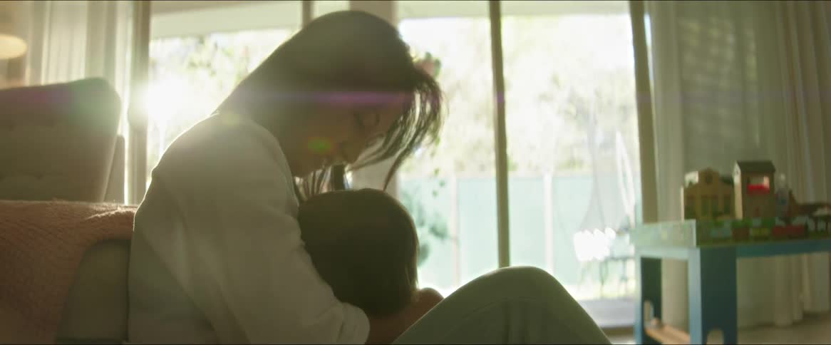 A mother coddles her toddler in a living room