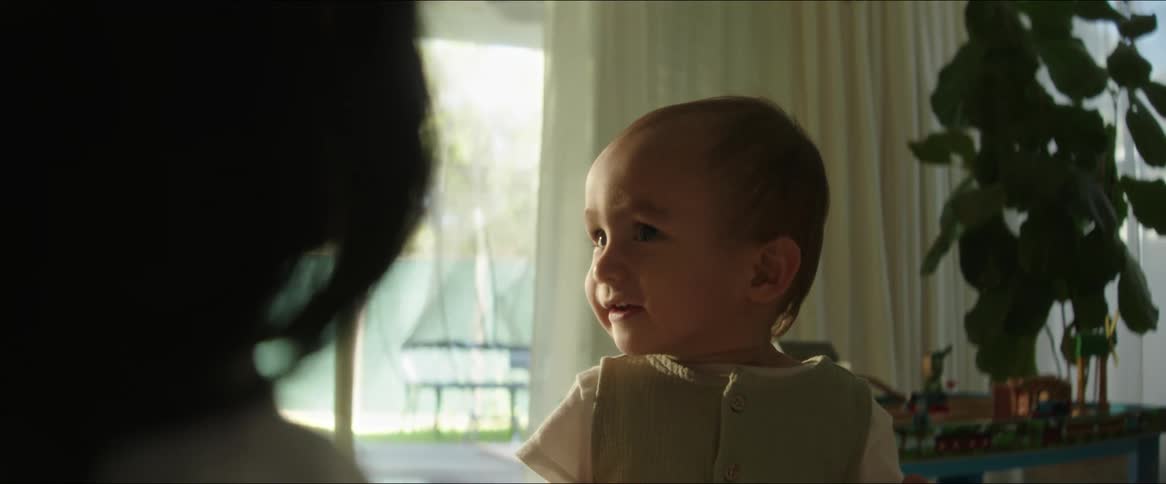 Toddler standing in the living room looks toward his mother