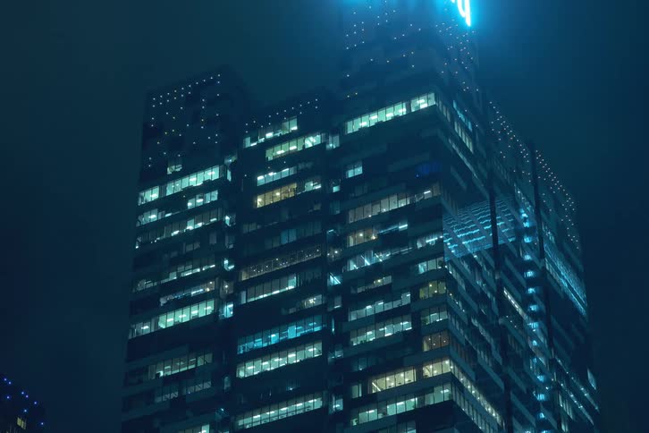 Modern building with window lights turning on seen at night