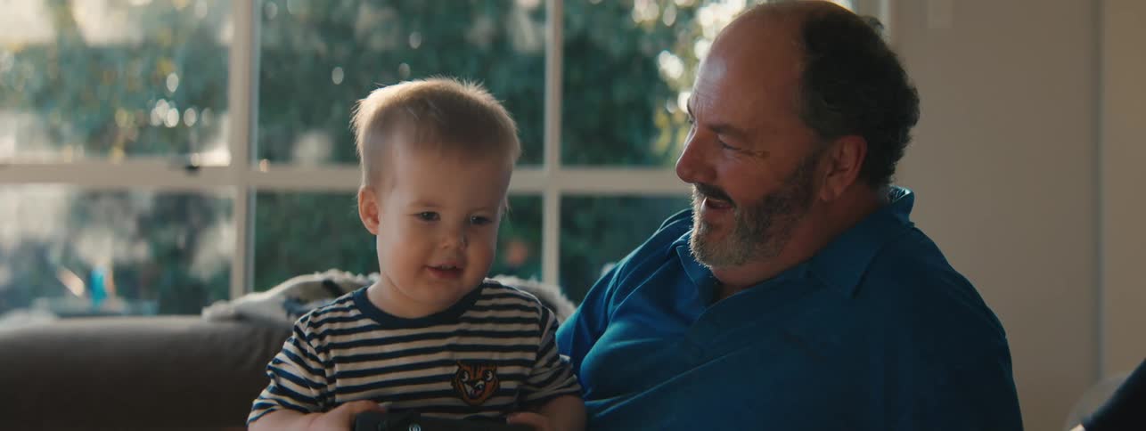 A son is sitting on his fathers lap
