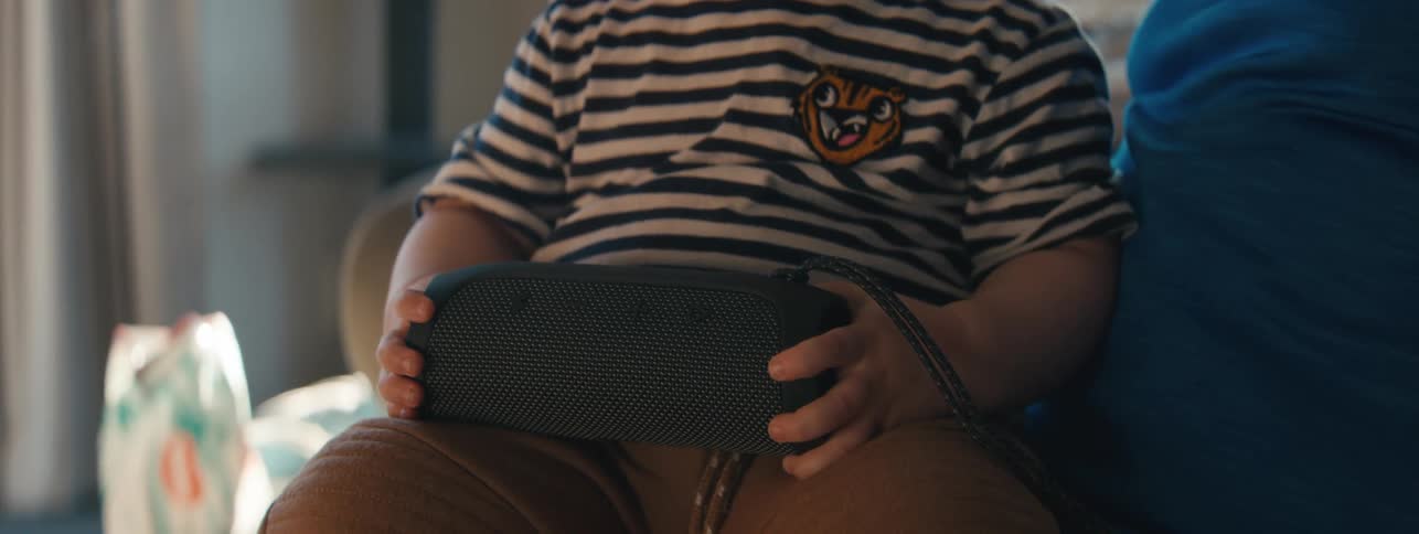 Little boy sitting interacting with a bluetooth speaker