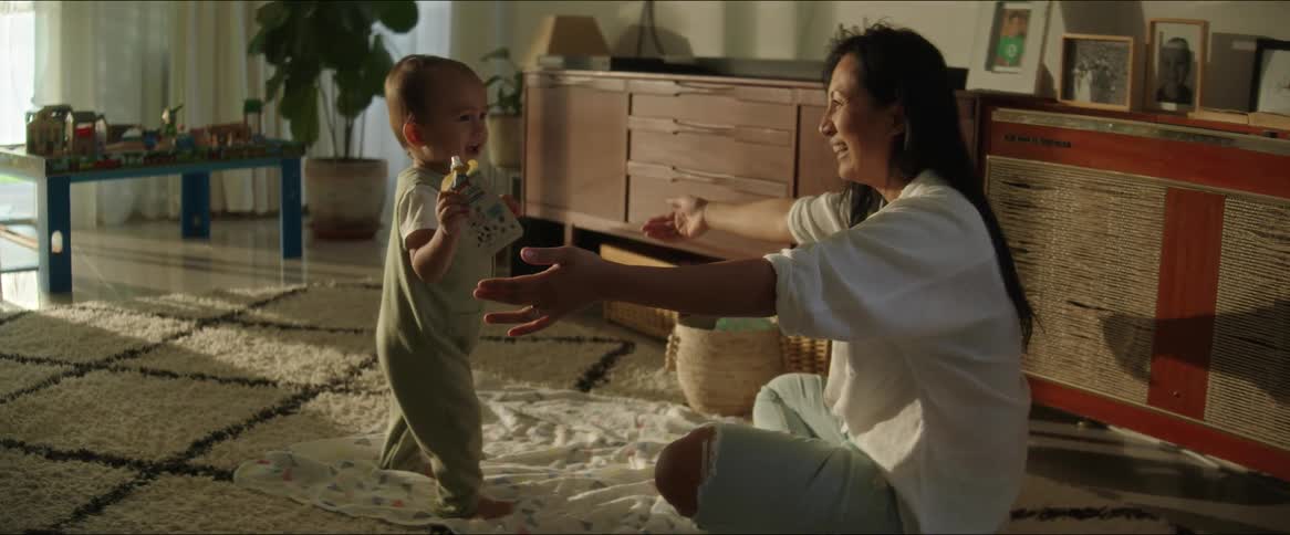 A baby walks towards his mother