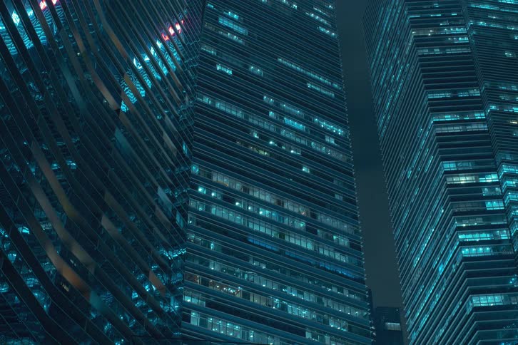 Lights flash on multiple floors inside city skyscrapers with the window lights turning on at night