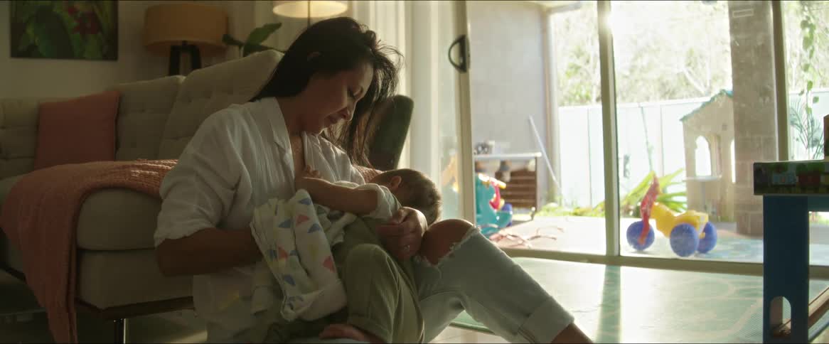 Mother slightly rocks her child while breastfeeding in their home