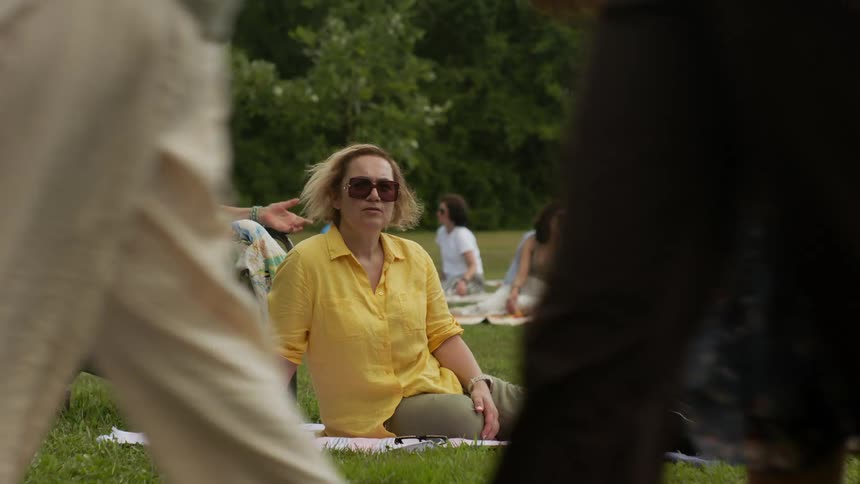 Group of women sitting on the grass watching people passing by
