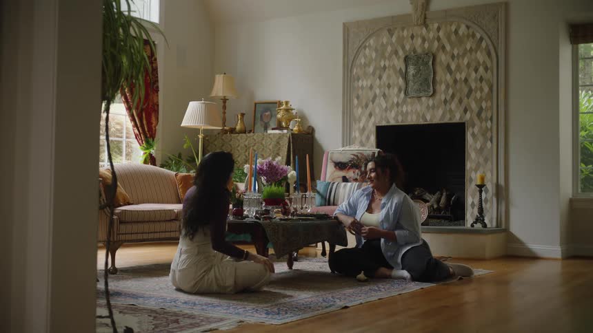 Two women sitting on the living room rug decorating a table