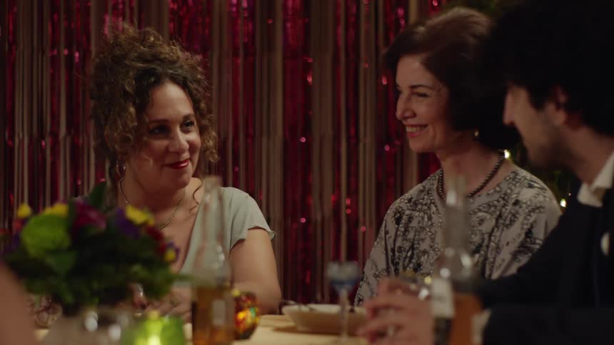 Man sitting with two ladies at a party table talking