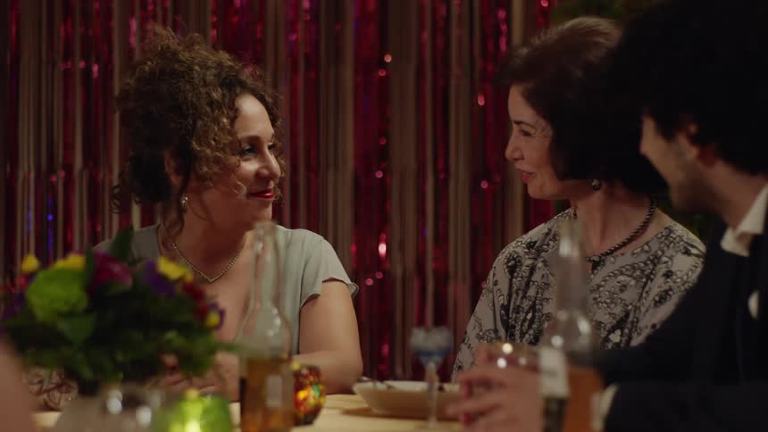 Friends dining at a dinner party smile while conversing together