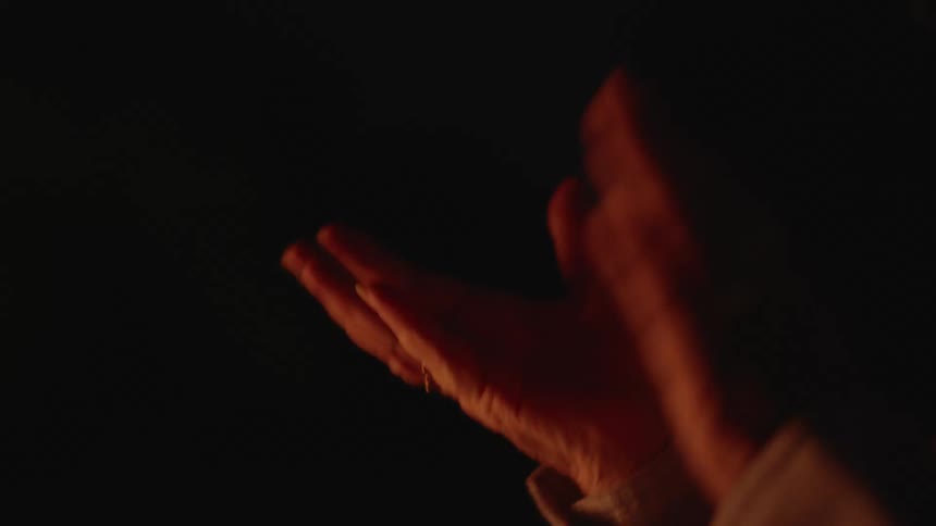 Person clapping while standing in a dark room