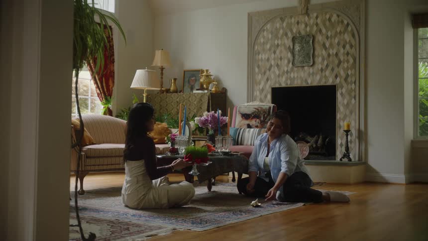 Two women sitting on the rug decorating a table in the living room