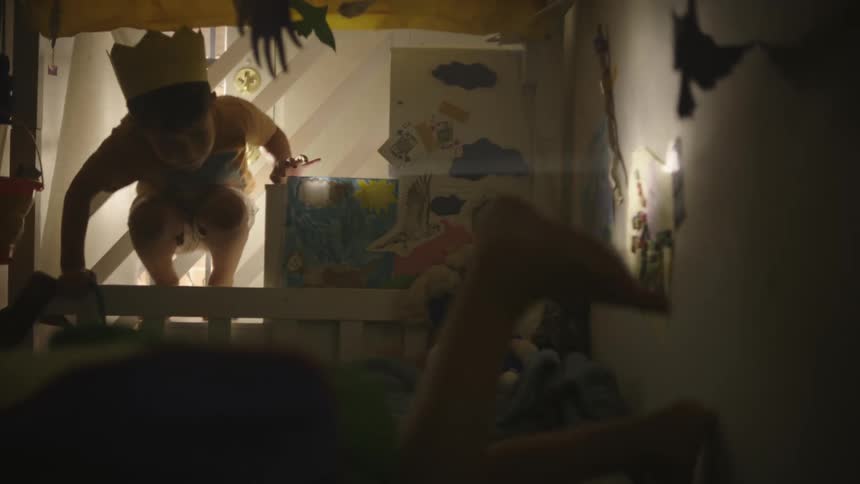 Two kids move around in a playing manner in a cramped bedroom