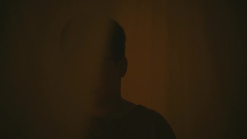 Youth closes his eyes and collapses between gauzy curtains