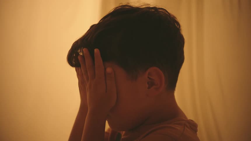 Youth standing between fluttering pieces of fabric covers his face
