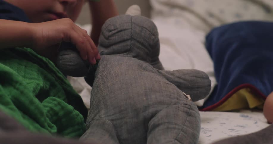 Boy lying down interacting with a teddy bear