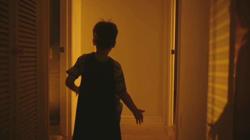 Boy wearing a cape and running in the hallway