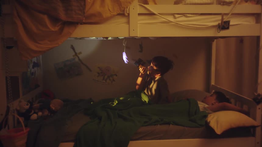 Two boys in a bunk bed with one of them playing with a flashlight