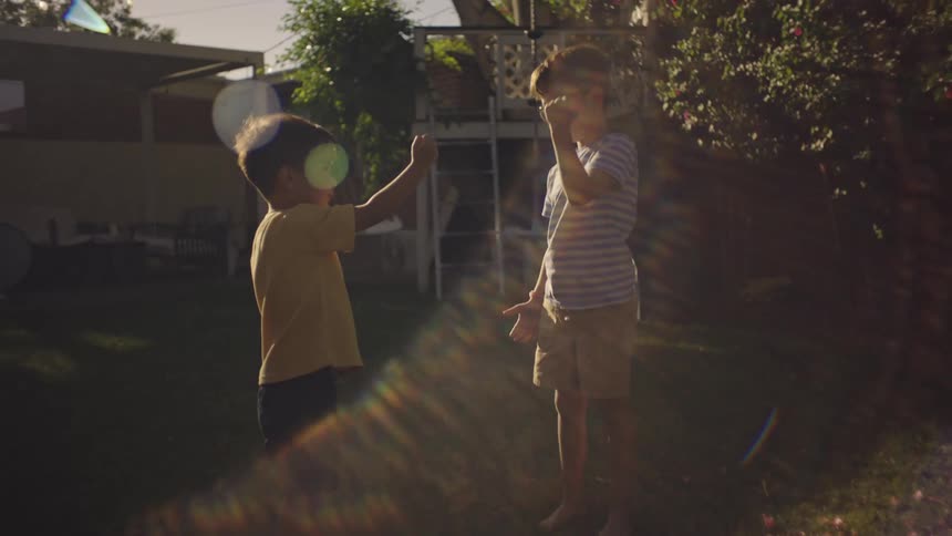 Two boys in the backyard with grass playing