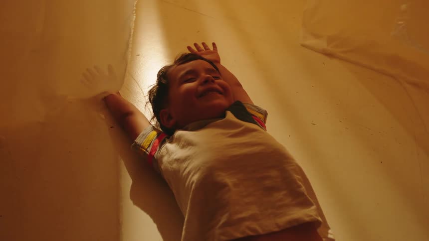 A child smiles while having his arms raised