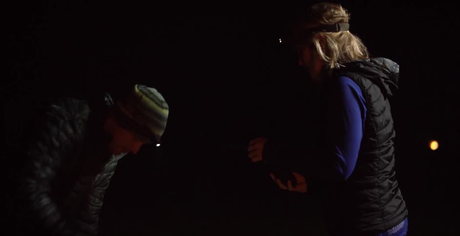 A man hands a woman something in a dark room