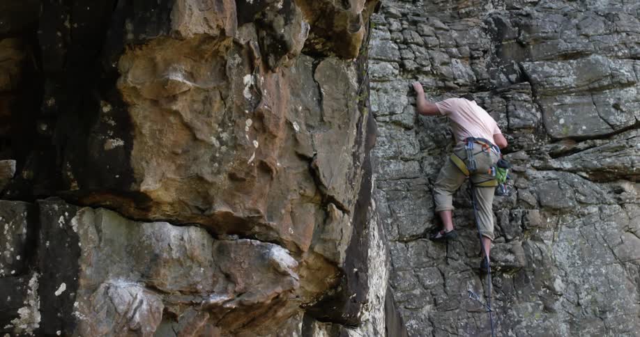A man climbs up a rocky cliffside