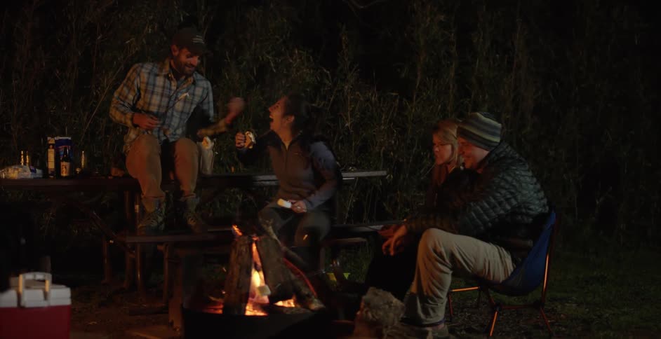 A group of people roast marshmallows around a campfire