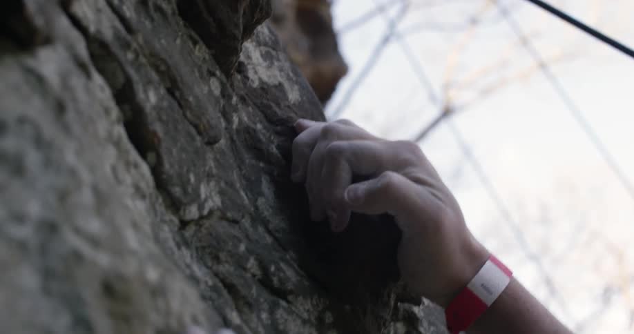 A person is gripping an outcropping on a rock face