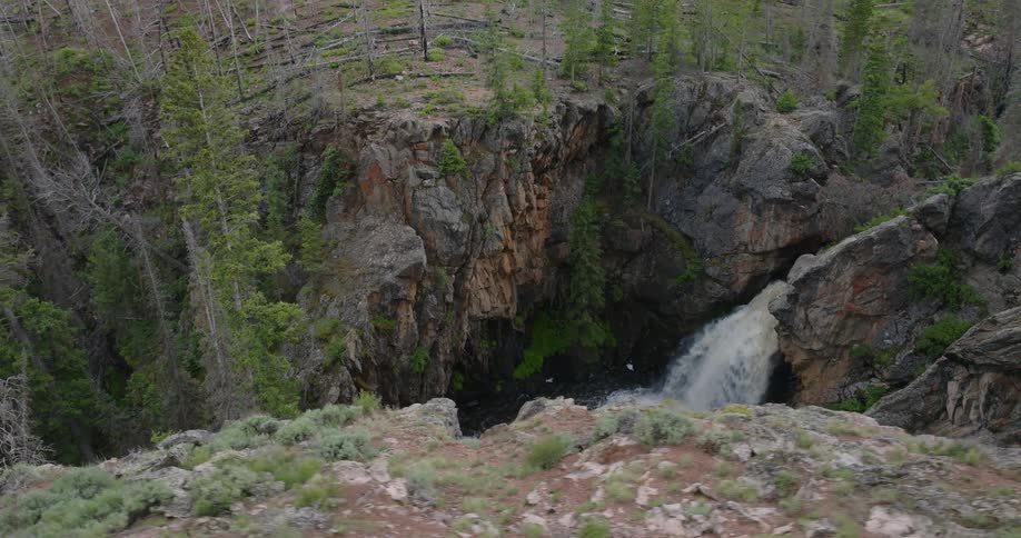 A waterfall drops over a mountain cliff