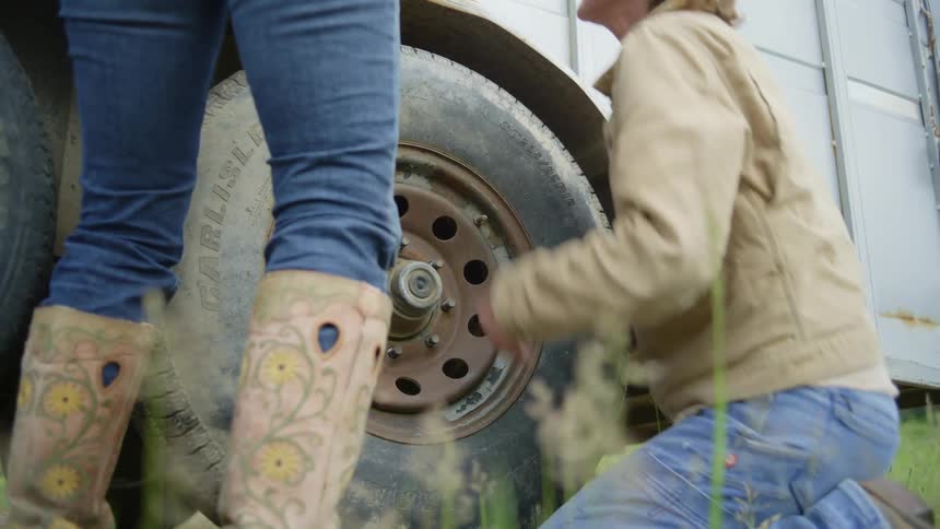 Two women adjusting a wheel on a pickup truck