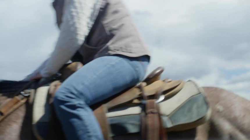 A cowboy rides a horse outdoors on a farm