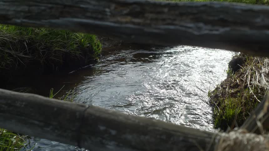 Flowing river seen from a wooden fence