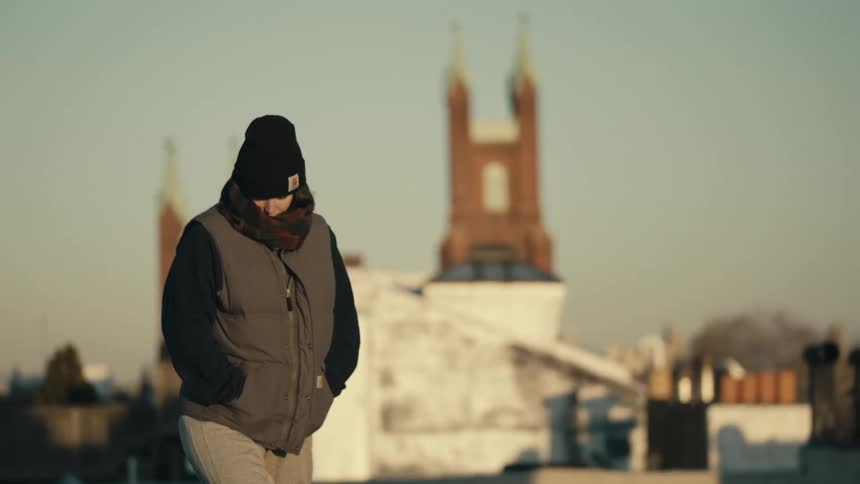 Person walking outside on a cold day with a city in the background