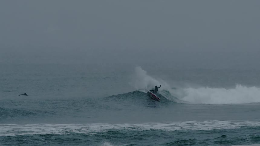Person doing a trick on a wave in the ocean on a snowy day