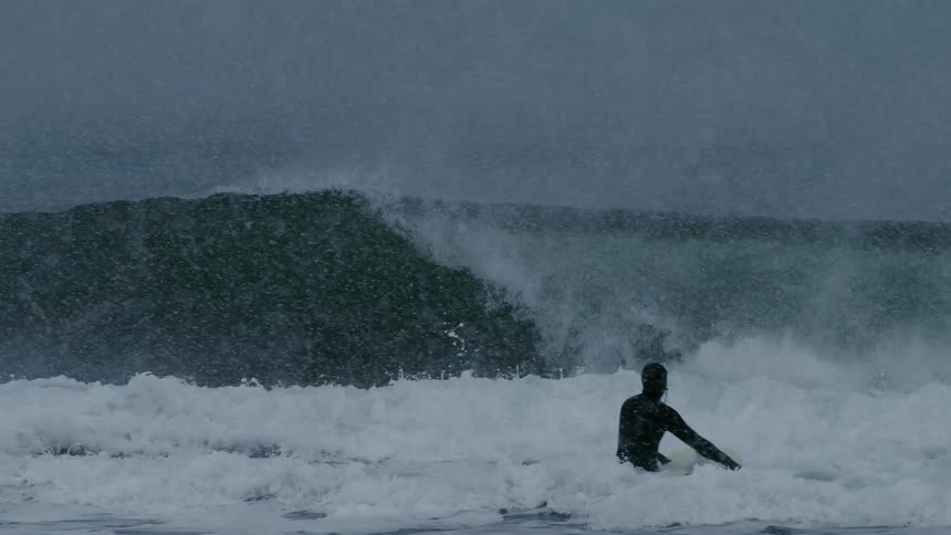 Surfer with his board heading towards a wave that breaks hard