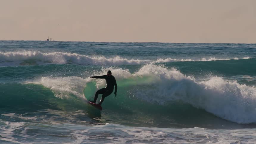 Person surfing a small wave in a rough sea