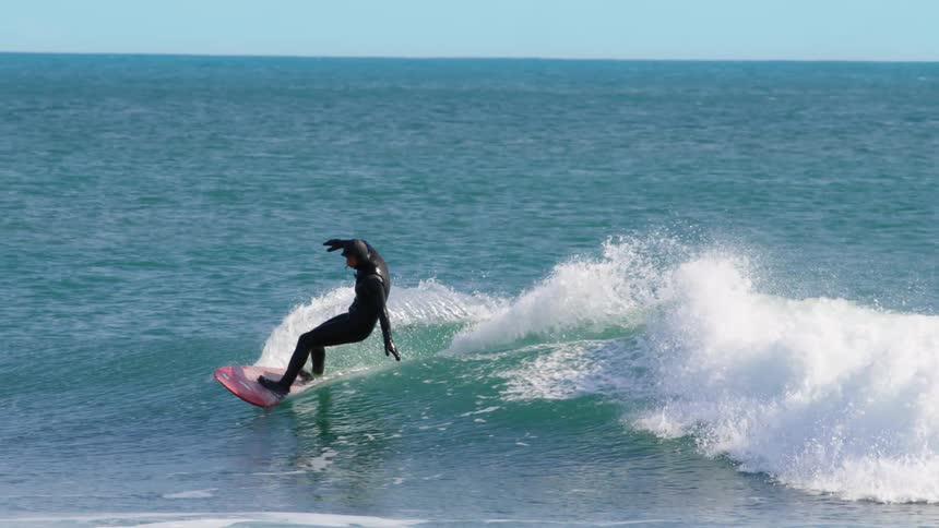 Person surfing a wave in a blue ocean