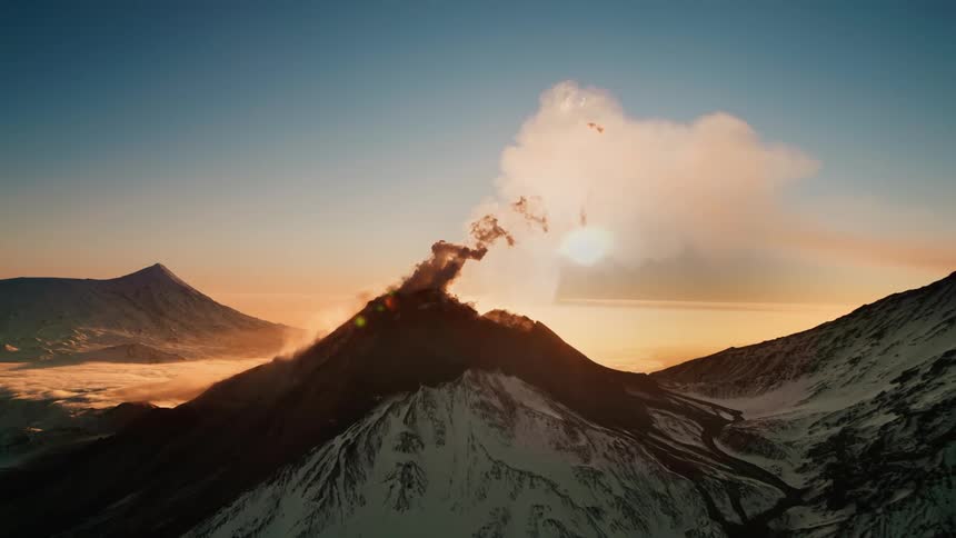 Aerial landscape of mountain ranges rising smoke with sun on horizon