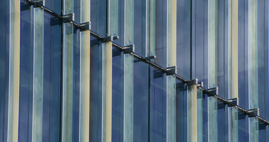 A closeup view of a modern buildings blue glass facade with visible vertical and horizontal metal supports