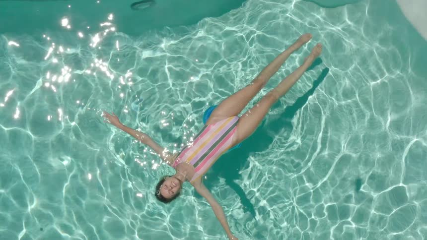 A person floats on their back in a blue pool