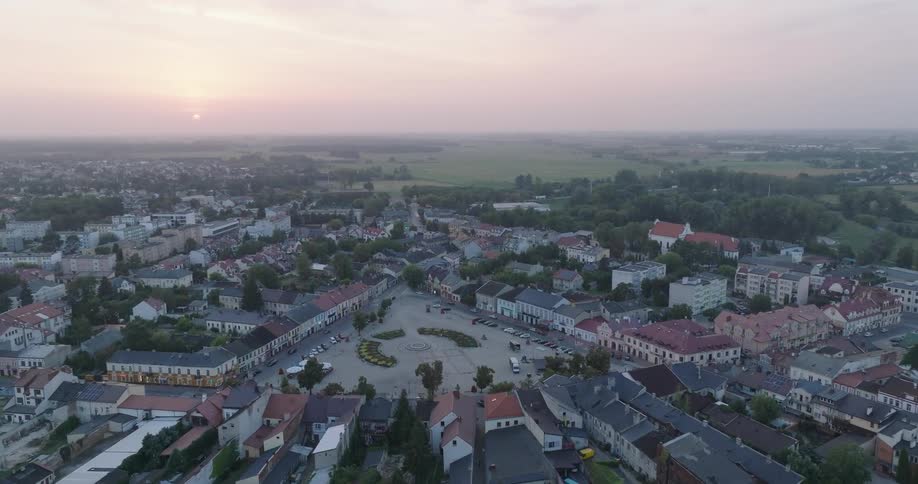 An aerial view of a town at dusk with buildings lining the streets and a central square