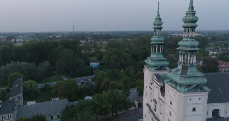 An aerial view of a town at sunrise or sunset with a church featuring two spires and domes