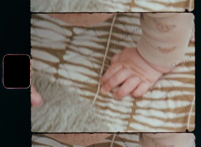The mother quickly tries to tickle her baby’s hand with her index finger as the baby crawls on a soft picnic blanket towards the lambskin or fur while they play outside in the garden spending quality family time