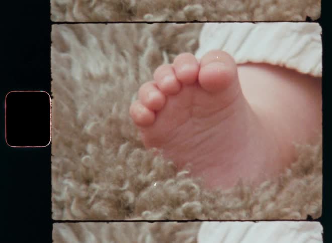 Close up of a baby’s foot and hand resting comfortably on a lamb or sheep skin touching the soft fur with the bare feet and tiny fingers feeling the sensory impression and developing the tactile sense while enjoying a careless and happy childhood